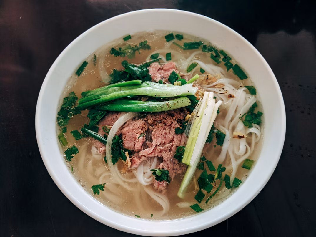 Bát phở bò nóng với hành và rau thơm